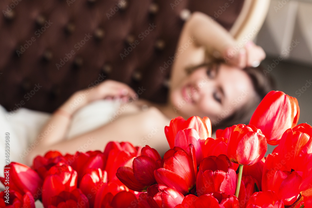 A bouquet of red tulips, and in the background a beautiful girl is posing. March 8 concept. Morning of the bride. A bouquet of red tulips, and in the background a beautiful girl is posing. March 8 concept. Morning of the bride.
