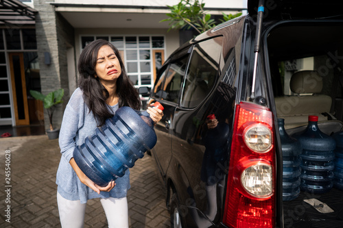 upset woman try to carry gallon of water photo