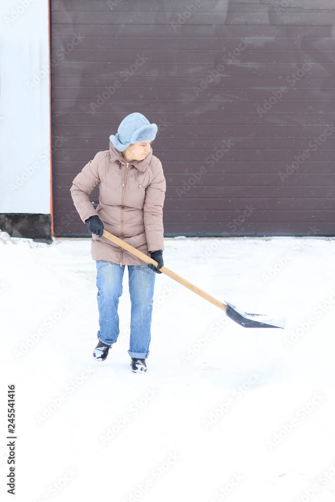 Obraz premium Winter is a lot of snow. A young girl, cleans, proud of doing the big shovel work