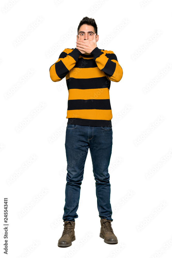 Full-length shot of Handsome man with striped sweater covering mouth with hands for saying something inappropriate on isolated white background Full-length shot of Handsome man with striped sweater covering mouth with hands for saying something inappropriate on isolated white background