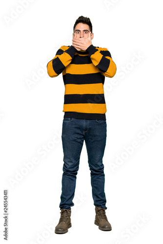 Fototapeta Naklejka Na Ścianę i Meble -  Full-length shot of Handsome man with striped sweater covering mouth with hands for saying something inappropriate on isolated white background