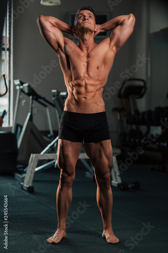 Young fit man doing bodybuilding competition poses