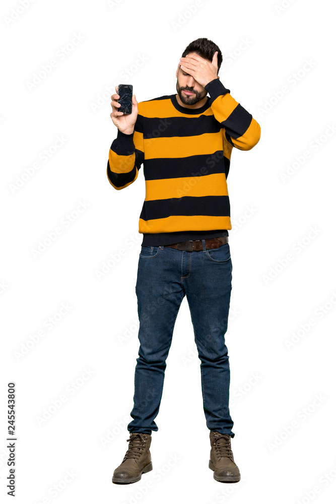Full-length shot of Handsome man with striped sweater with troubled holding broken smartphone on isolated white background Full-length shot of Handsome man with striped sweater with troubled holding broken smartphone on isolated white background