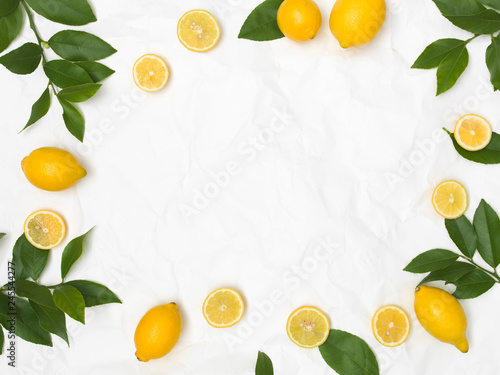 Fototapeta Naklejka Na Ścianę i Meble -  many fresh lemons and green leaves on white crumpled paper background