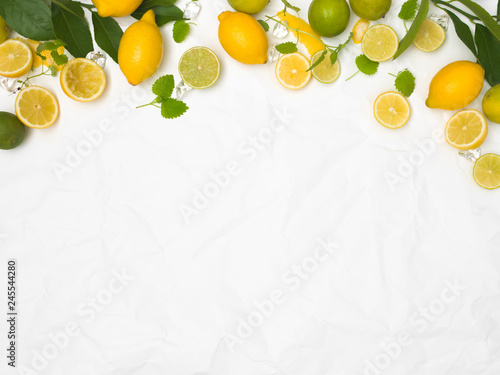 Canvas Print many fresh lemons and limes and green leaves on white crumpled paper background