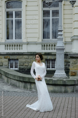 beautiful girl in wedding dress with long tule train standing alone