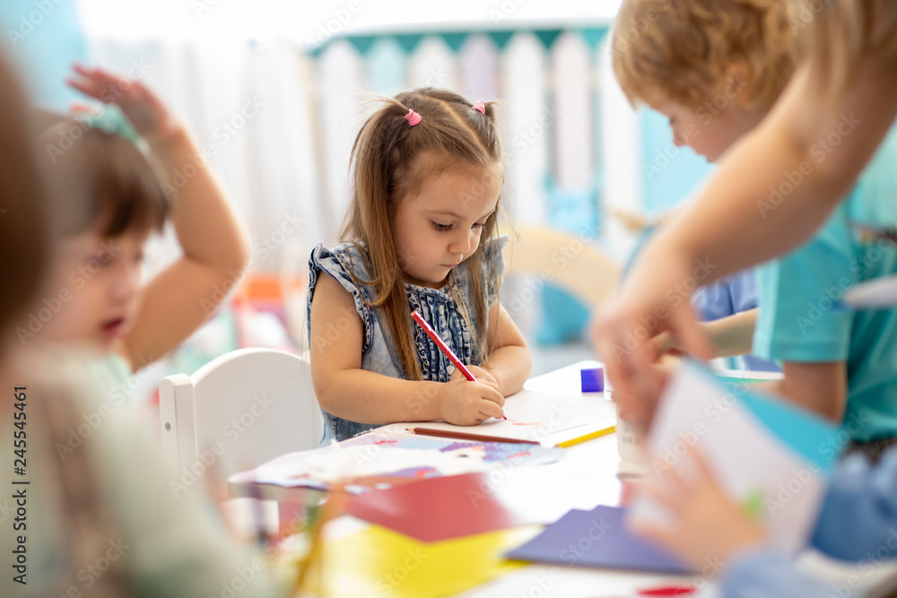Group of children drawing with nursery teacher in kindergarten Group of children drawing with nursery teacher in kindergarten
