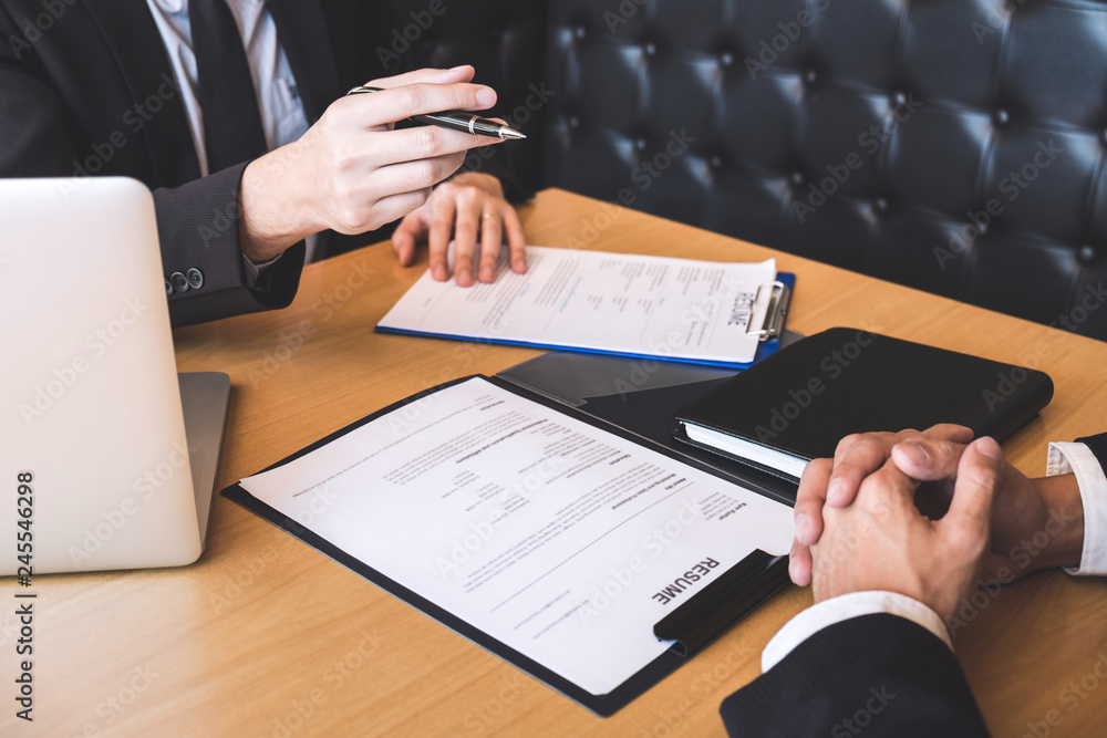 Employer or recruiter holding reading a resume during about his profile of candidate, employer in suit is conducting a job interview, manager resource employment and recruitment concept Employer or recruiter holding reading a resume during about his profile of candidate, employer in suit is conducting a job interview, manager resource employment and recruitment concept