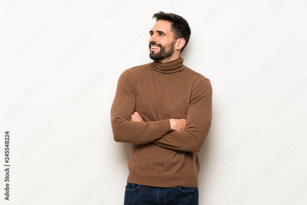 Handsome man over white wall keeping the arms crossed while smiling Handsome man over white wall keeping the arms crossed while smiling