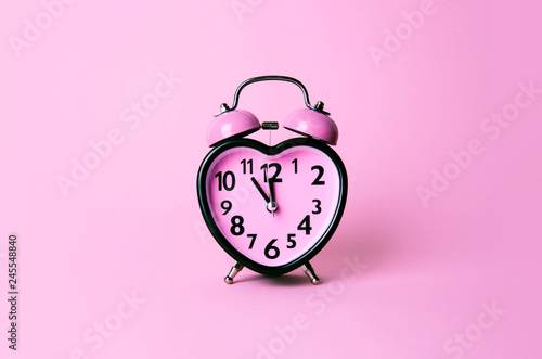 Heart shaped clock on pink background.