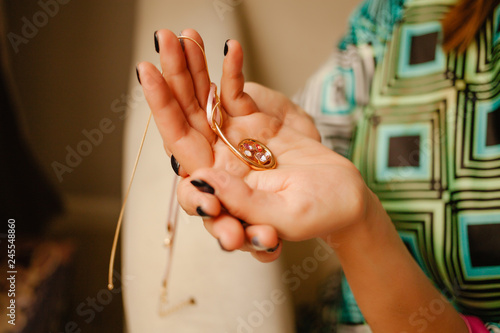 Woman's hand holding stylish necklace.