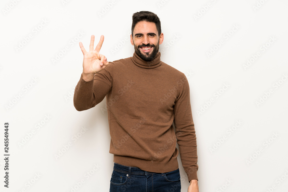 Handsome man over white wall happy and counting three with fingers Handsome man over white wall happy and counting three with fingers