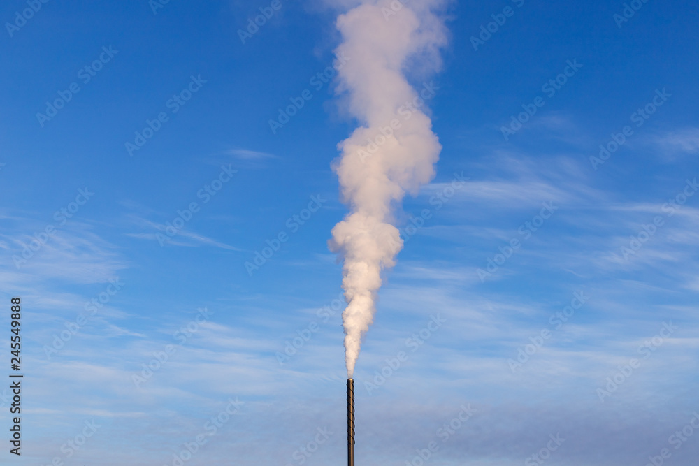 Cloud of white smoke from industrial chimney against blue clear sky