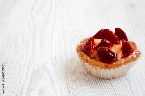 Strawberry vanilla cream cheese tarts on white wooden background  low angle view. Copy space.