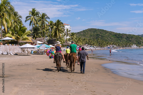 Turistas pasean en caballos en la playa de Manzanillo Colima. photo