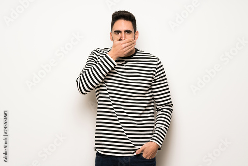 handsome man with striped shirt covering mouth with hands for saying something inappropriate