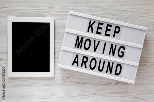 'Keep moving around' words on modern board, tablet on a white wooden surface, top view. From above, flat lay, overhead.