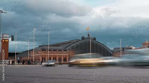 Timelapse traffic rush hour in Emperor Charles V square, with Madrid Atocha railway station on the background in Madrid, Spain.