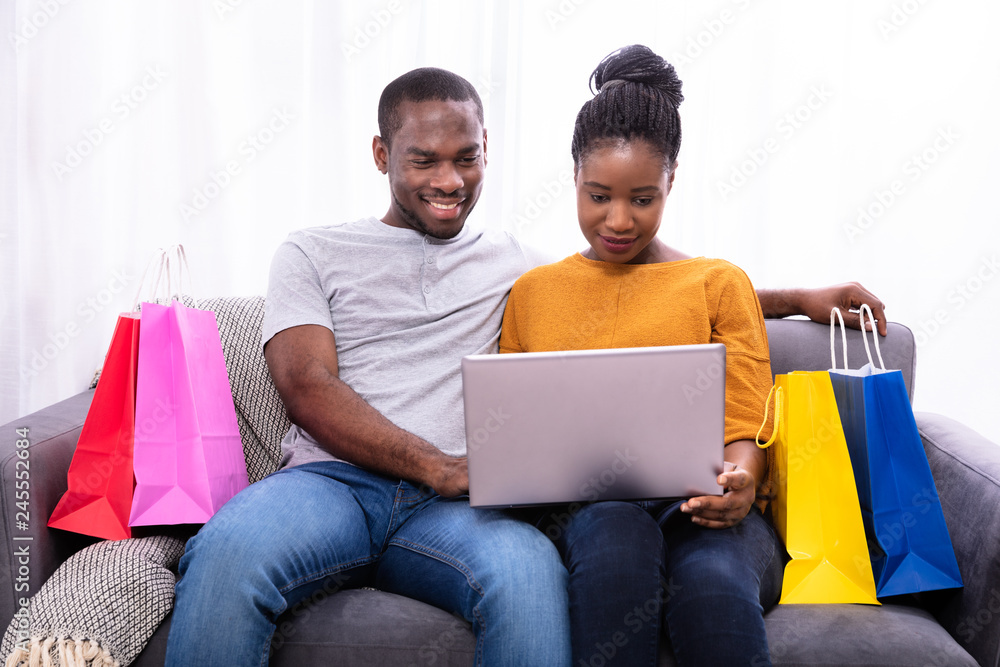 Smiling Young Couple Shopping On Laptop