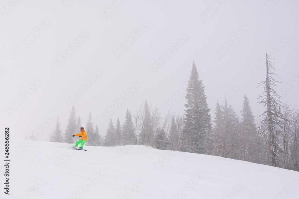 Snowboarder in bright outfit is making freeride shred while windy blizzard Snowboarder in bright outfit is making freeride shred while windy blizzard