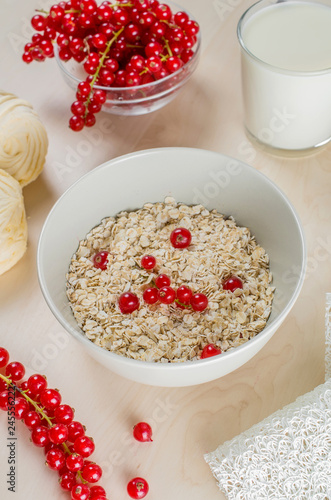 Breakfast served with oatmeal, a glass of milk, cranberry and marshmallow on a wooden background
