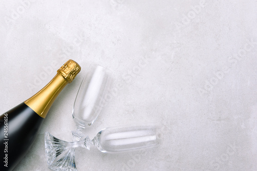 Champagne bottle and glasses on light gray surface.
