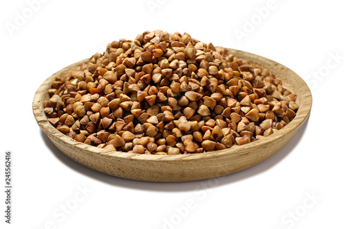 A full wooden plate of buckwheat groats, isolated on a white background. Buckwheat.