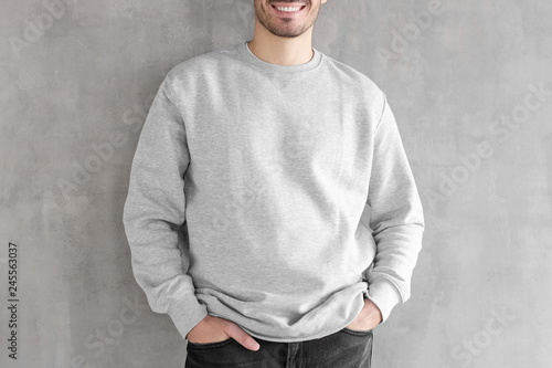 Mock up shot of young man body in empty sweatshirt isolated on textured gray wall background. No face photo