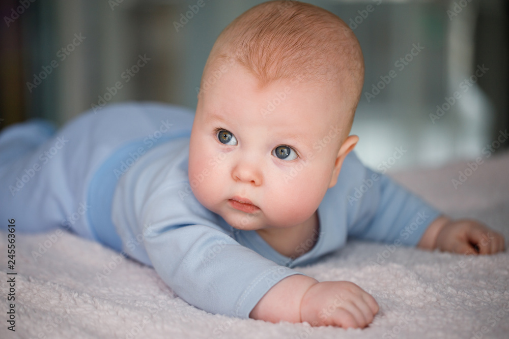 Portrait of a baby boy who lies on his stomach in a blue suit Portrait of a baby boy who lies on his stomach in a blue suit