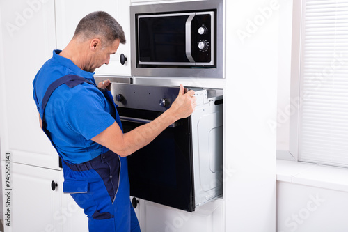 Fotografija Technician In Overall Installing Oven