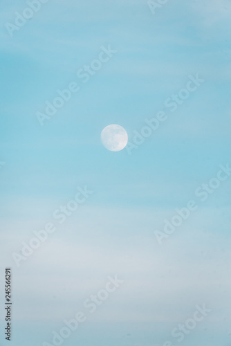 The moon in a blue daytime sky