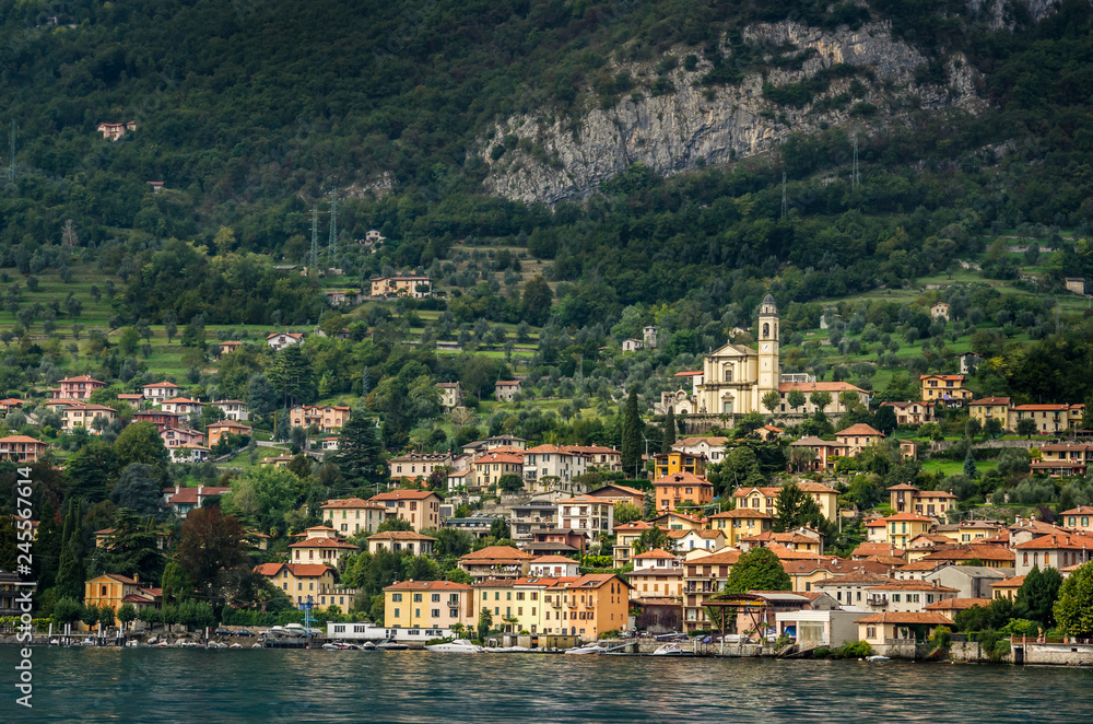 View of village in forest in Lake Como from ferry at sunset, Lake Como, Italy