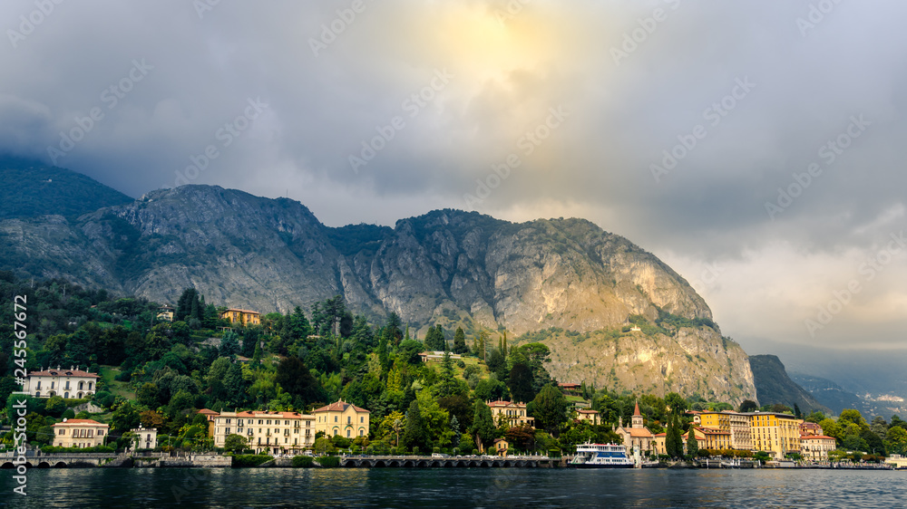 View of village with halo light in forest in Lake Como from ferry at sunset, Lake Como, Italy
