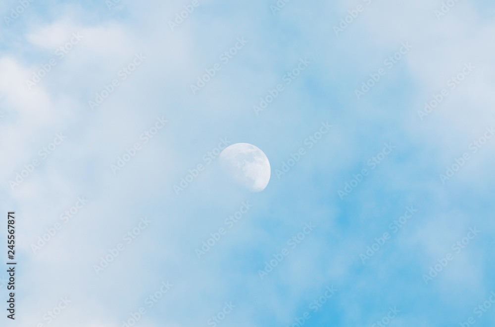 Half bright moon on blue sky background with clouds on day time Half bright moon on blue sky background with clouds on day time