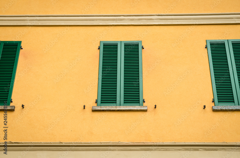 Traditional Mediterranean window with closed green shutters, Village in Lake Como, Italy.