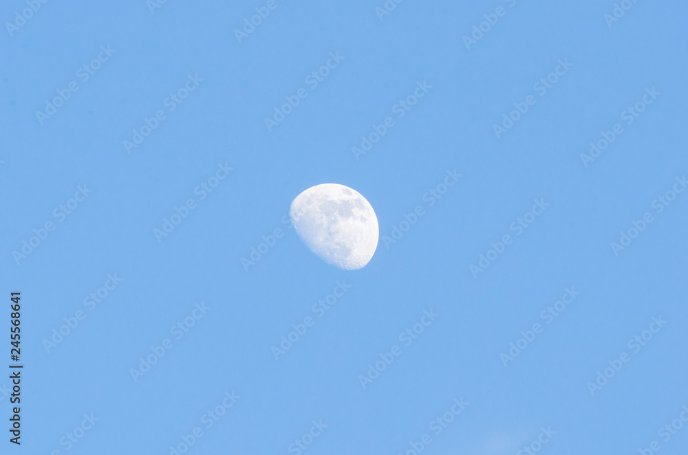 Half bright moon on blue sky background with clouds on day time Half bright moon on blue sky background with clouds on day time