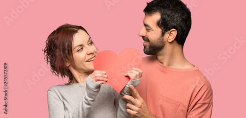 Couple in valentine day holding a heart symbol over isolated pink background