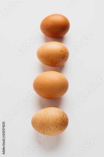 Different brown zwf on a white background lie in a row behind each other. Four chicken fresh delicious eggs in a row.