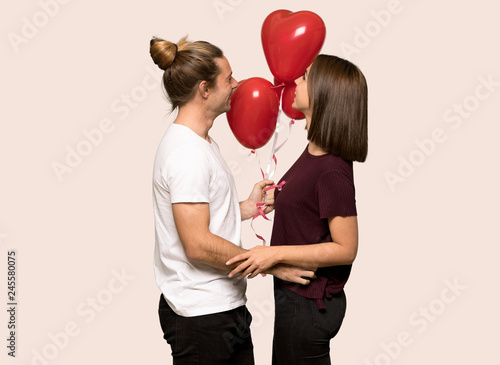 Couple in valentine day with balloons with heart shape over isolated background © luismolinero