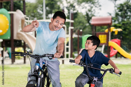 Father and child riding a bicycle in the playground