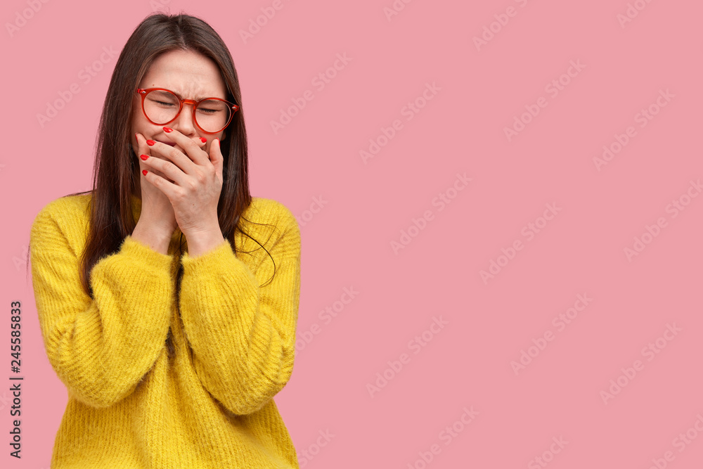 Φωτογραφία Doleful depressed woman cries desperately, being in grief, covers mouth with palms, wears casual clothes, models over pink background with copy space for your promotional content or advertisement