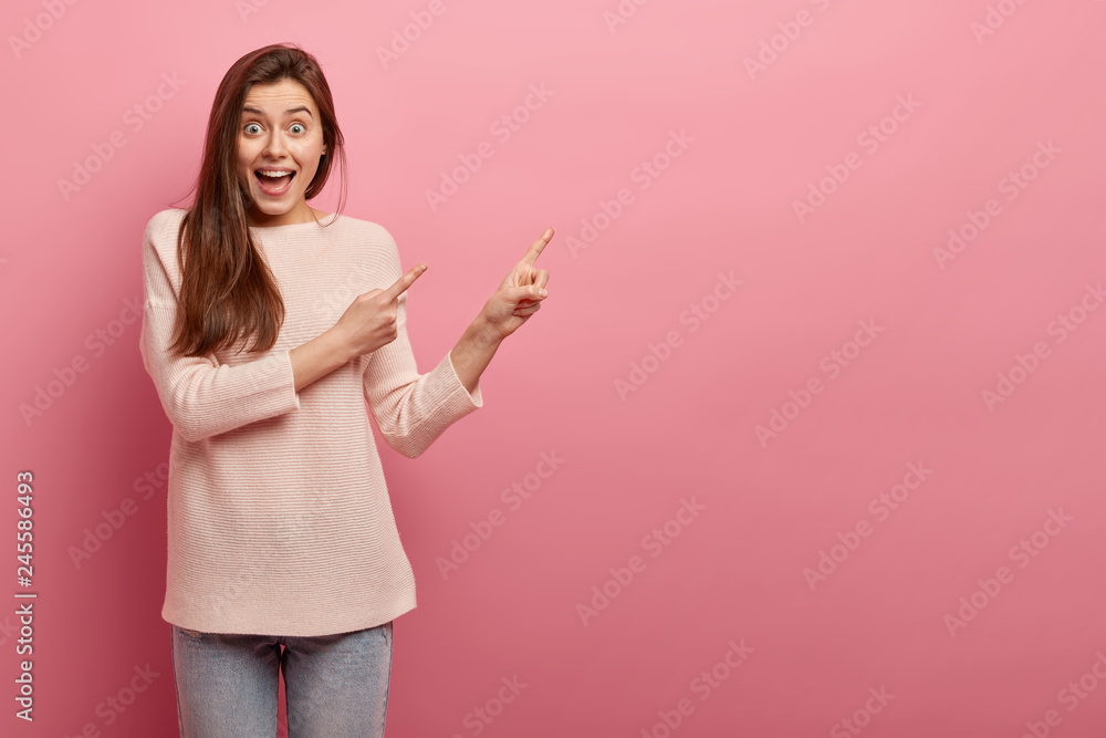 Pleased dark hared woman with long hair, has amazed joyful expression, indicates at upper right corner with index fingers, dressed in casual clothes, isolated over pink studio wall. Advertisement Pleased dark hared woman with long hair, has amazed joyful expression, indicates at upper right corner with index fingers, dressed in casual clothes, isolated over pink studio wall. Advertisement