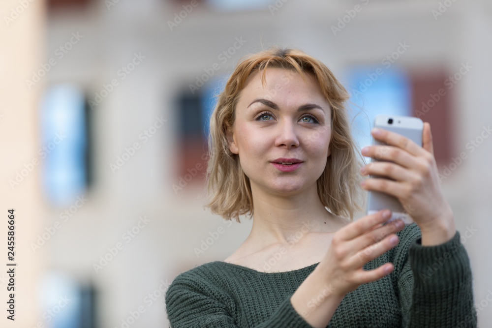 blonde young girl in the city happy with the mobile blonde young girl in the city happy with the mobile