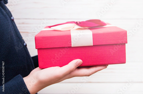 Real box with white and red bow and ribbon in girl s hands on Valentine's day isolated on white background. Copy space