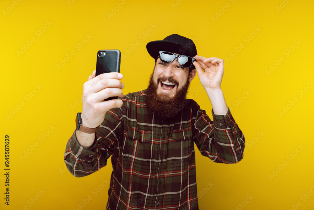 Portrait of bearded man in hat and sunglasss looking confused at news feed Portrait of bearded man in hat and sunglasss looking confused at news feed