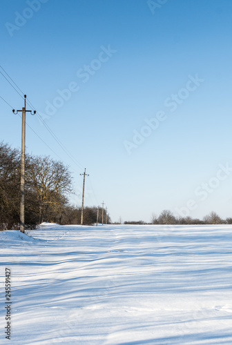Power line in the winter on the outskirts of the village, snowy road