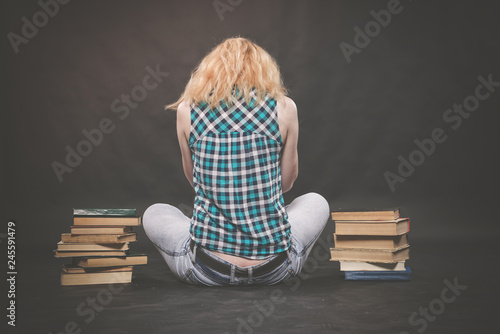 teen girl sitting on the floor next to books and emotionally showing her hatred, hate and fatigue