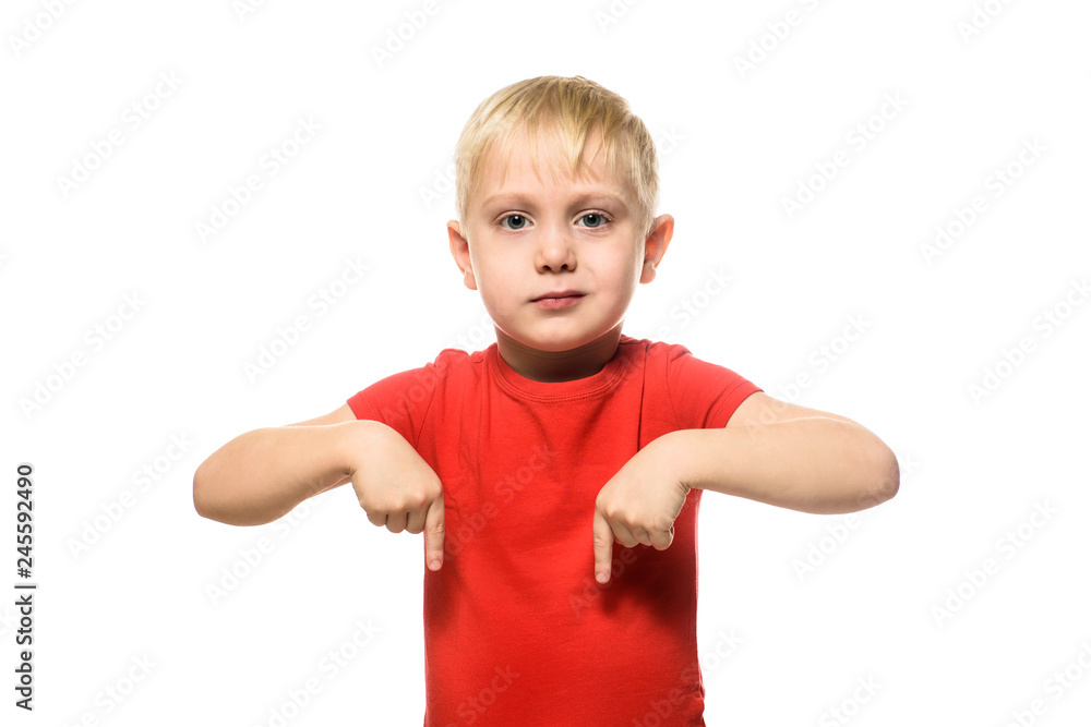 Serious little blond boy in a red shirt stands and shows index fingers down. Isolate on white background. Serious little blond boy in a red shirt stands and shows index fingers down. Isolate on white background.