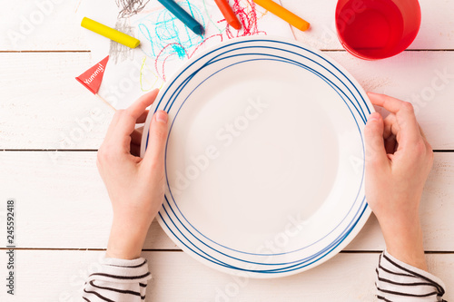 Table setting for kids - empty plate in child's hands