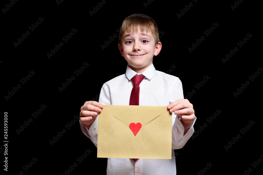 Fair-haired boy in a shirt and tie holds an envelope with a heart. Isolate on black background. Fair-haired boy in a shirt and tie holds an envelope with a heart. Isolate on black background.